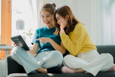 İki Asyalı kadın evdeki koltuklarında online pazarlıklarla seviniyor..