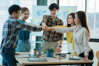 Genç Asyalılar el sıkışarak ve el sıkışarak başarılı bir iş kurmayı kutluyorlar..