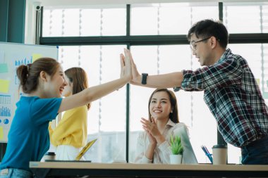 Genç Asyalılar el sıkışarak ve el sıkışarak başarılı bir iş kurmayı kutluyorlar..