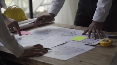 Çok ırklı mühendisler, mimarlar inşaat planlarını tartışıyor. Mühendisler, planlama ve takım çalışması fikirlerinin başarılı mühendislik planları üzerinde çalışıyorlar. 4K Video
