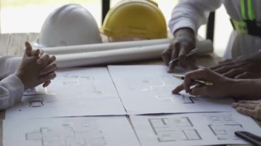 Çok ırklı mühendisler, mimarlar inşaat planlarını tartışıyor. Mühendisler, planlama ve takım çalışması fikirlerinin başarılı mühendislik planları üzerinde çalışıyorlar. 4K Video