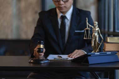 Asyalı erkek avukat ofisi çekiç ve teraziyle çalışıyor. Adalet tanrısı ve dizüstü bilgisayar. Akıllı telefon sözleşmesi belgeleriyle online yasal danışmanlık kavramı.