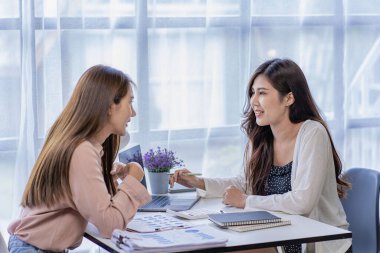 Mali analiz yapan iki Asyalı kadın. Toplantıda fikir alışverişinde bulunan iki iş kadını..