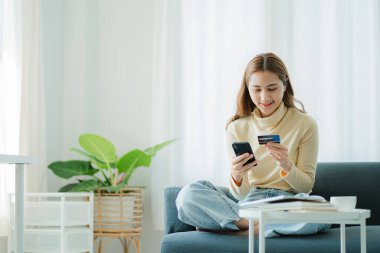 Asya Taylandlı güzel kahverengi kız cep telefonu ve kredi kartı ile siteye kaydolmuş. Bir iş kadını internetten alışveriş yaparken kredi kartıyla ödeme yapar..