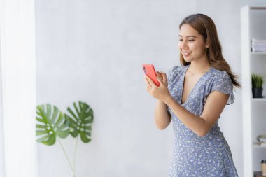 Akıllı telefondan konuşan Asyalı bir kadın, evden çalışıyor, dijital telefon teknolojisi yaşam tarzı evde çalışıyor ve dizüstü bilgisayar finansal konseptiyle çalışıyor.
