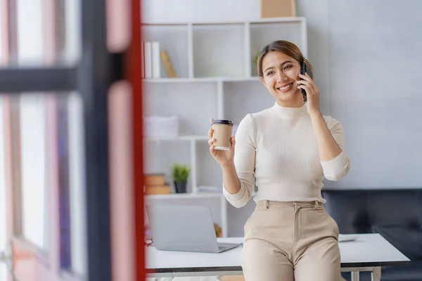 stock image Asian woman talking on smartphone, working from home, digital phone technology lifestyle work from home with laptop financial concept