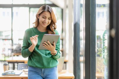 Evde tablet kullanarak çalışan başarılı Asyalı iş kadını. İnternette sörf yapmak sosyal medya yaratıcı planlama işi