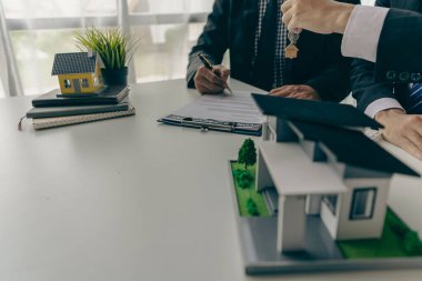 Emlak satış temsilcileri krediler ve faiz oranları hakkında konuşur, ev satın alma sözleşmeleri sunar ev veya daire satın almak için ve ofisteki bir müşteriye ev anahtarı verir.