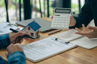 Emlak satış temsilcileri krediler ve faiz oranları hakkında konuşur, ev satın alma sözleşmeleri sunar ev veya daire satın almak için ve ofisteki bir müşteriye ev anahtarı verir.