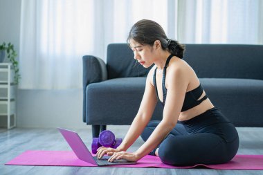 Halter kullanarak egzersiz yapan Asyalı bir kadın yoga yapan, meditasyon yapan, evde gezen spor kıyafetleri giyen, vücut fotoğrafı çeken ve meditasyon yapan güzel bir kadın. sağlıklı yaşam tarzı