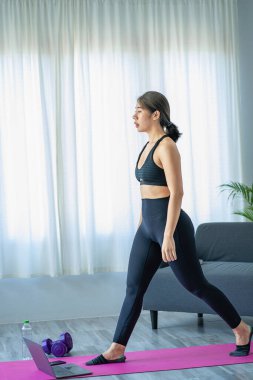 Halter kullanarak egzersiz yapan Asyalı bir kadın yoga yapan, meditasyon yapan, evde gezen spor kıyafetleri giyen, vücut fotoğrafı çeken ve meditasyon yapan güzel bir kadın. sağlıklı yaşam tarzı