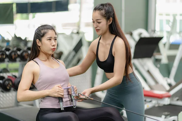 ジムで働く2人のアジアの女性がトレッドミルのランニングマシンで走るスポーツウェアでアジアの女性をロープで引っ張るトレーニング 健康とフィットに焦点を当て続ける — ストック写真