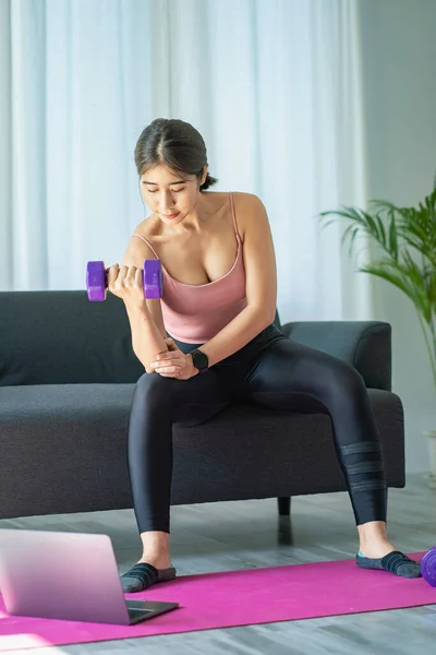 stock image Asian woman exercising using dumbbells Beautiful woman practicing yoga, meditating, indoors at home, wearing sportswear, taking a full body photo and practicing meditation. healthy lifestyle