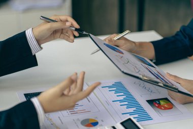 İş adamları veri grafiklerini analiz etmek ve tartışmak ve tartışmak için toplanıyor. Finansal raporlar, mali danışmanlar, takım çalışması ve muhasebe kavramları ofis masası harcamaları