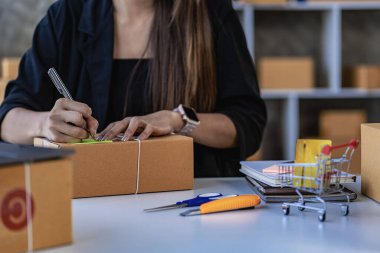 KOBİ işi, evde online satışlar, müşterilerden sipariş almak için kutularla ve dizüstü bilgisayarlarla çalışan Asyalı kadın, paket teslimat konsepti, çevrimiçi iş KOBİ 'si