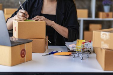 KOBİ işi, evde online satışlar, müşterilerden sipariş almak için kutularla ve dizüstü bilgisayarlarla çalışan Asyalı kadın, paket teslimat konsepti, çevrimiçi iş KOBİ 'si