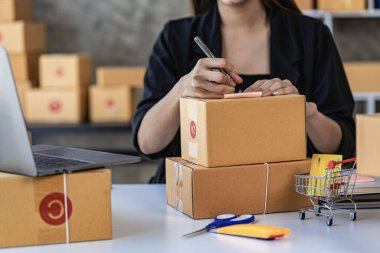KOBİ işi, evde online satışlar, müşterilerden sipariş almak için kutularla ve dizüstü bilgisayarlarla çalışan Asyalı kadın, paket teslimat konsepti, çevrimiçi iş KOBİ 'si