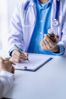 Doktorlar ve hastalar oturup hastalarla ilaçlar hakkında konuşurlar. Hastanenin penceresinin yanındaki masada kadın doktor konuşuyor, küçük hastayı muayene ediyor ve doktor not alıyor..