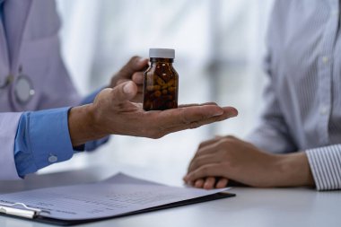 Doktorlar ve hastalar oturup hastalarla ilaçlar hakkında konuşurlar. Hastanenin penceresinin yanındaki masada kadın doktor konuşuyor, küçük hastayı muayene ediyor ve doktor not alıyor..