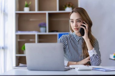 İş araştırma ve analiz konsepti ofisinde başarılı işler için fikir ve gereksinimler edinmek amacıyla akıllı telefondan müşterilere gülümseyen ve onlarla konuşan Asyalı çekici iş kadını.