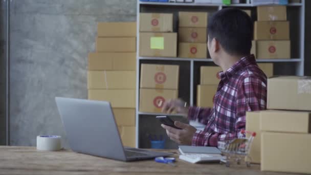 Молодой Человек Разговаривает Смартфоне Использует Ноутбук Продажи Продуктов Интернете Дому — стоковое видео