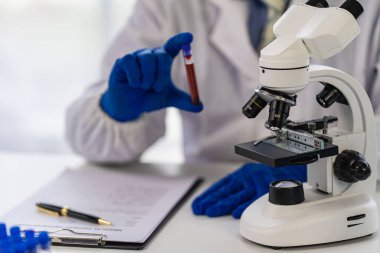 Tıbbi araştırma ve geliştirme konseptleri için klinik laboratuarında damar sağlığı doktoru. Bir mikroskop ve yanına yerleştirilmiş bir test tüpü ile bilim.