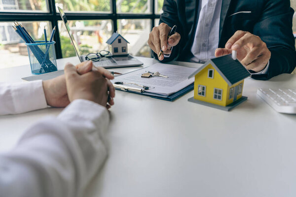 Агенты по недвижимости рекомендуют дома и предлагают клиентам страховые процентные ставки в офисе идеи покупки жилья.