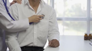 Steteskoplu bir kadın doktor hastayı muayene ediyor. Hastanede, bir kardiyolog muayene sırasında bir erkeğin kalp atışlarını kontrol eder. kalp sağlığı konsepti