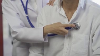 Steteskoplu bir kadın doktor hastayı muayene ediyor. Hastanede, bir kardiyolog muayene sırasında bir erkeğin kalp atışlarını kontrol eder. kalp sağlığı konsepti