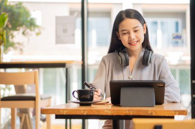 Asyalı kadın kulaklık takıyor, dizüstü bilgisayar izliyor, özel hocayla çevrimiçi öğrenmenin tadını çıkarıyor. Sesli anlatımı dinle Webinar 'ı izle