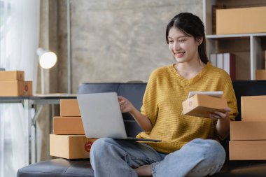Genç girişimci küçük işletme sahibi ev ambalaj ve teslimat işinde çalışıyor Asyalı kadın KOBİ işletmecileri online alışveriş için dizüstü bilgisayarlar üzerinde çalışıyorlar. Neşeli ve mutlu KOBİ başlangıç iş fikri
