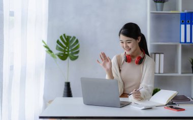 Kırmızı kablosuz kulaklık takan Asyalı kız öğrenci çevrimiçi öğrenim konsepti