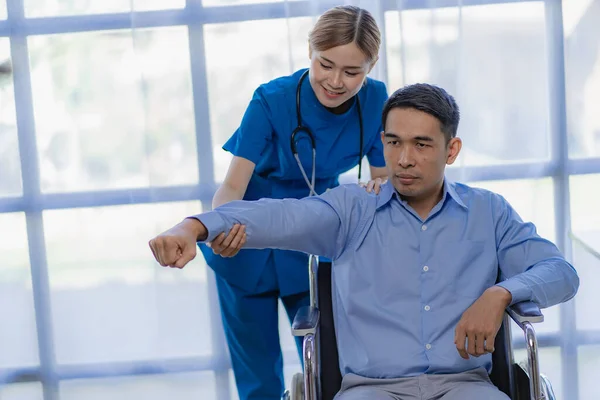 亚洲女医生对有腕部和肩部疼痛的男性患者进行理疗 — 图库照片