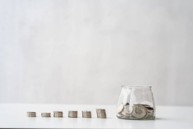 Para biriktir. Gri arka planda para yığınının yanındaki kumbarayla kişisel finans planlama ve tasarruf konsepti.