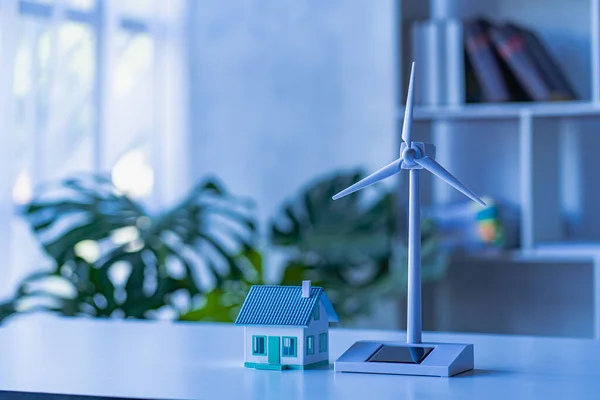 stock image Ecology, technology and energy saving concepts. toy house model and wind turbines with alternative renewable energy in a clean electric energy future.