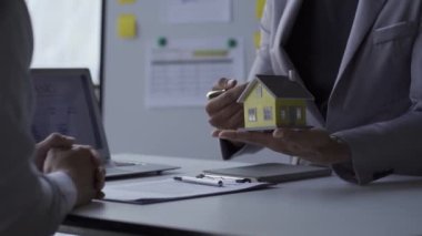 Emlakçılar müşterilerine ev kredisi anlaşması teklif ediyor. ve müşteri sigortası, anahtarlıklar ve banka kredisindeki oyuncak evler veya emlak kiralama sözleşmeleri, 4k video.