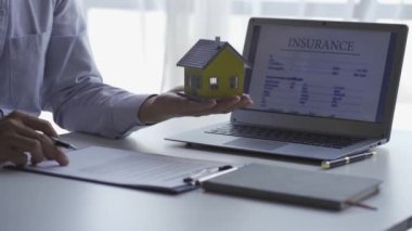 Emlakçılar müşterilerine ev kredisi anlaşması teklif ediyor. ve müşteri sigortası, anahtarlıklar ve banka kredisindeki oyuncak evler veya emlak kiralama sözleşmeleri, 4k video.
