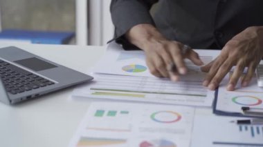 Dizini dizin, mali raporlar ve iş çizelgeleriyle kontrol eden yönetici kağıt tabanlı grafik analiz belgeleri üzerinde çalışıyor..