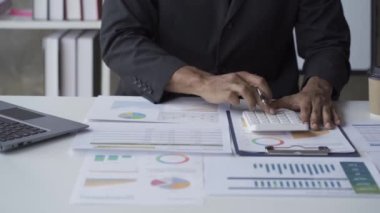 Dizini dizin, mali raporlar ve iş çizelgeleriyle kontrol eden yönetici kağıt tabanlı grafik analiz belgeleri üzerinde çalışıyor..