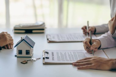 Emlakçılar, taksitle bir konut satın almanın faiz oranı anlaşmasının şartlarını tartışıyor. Müşterilerden kontrat imzalamalarını isteyin.