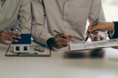 Emlakçılar, taksitle bir konut satın almanın faiz oranı anlaşmasının şartlarını tartışıyor. Müşterilerden kontrat imzalamalarını isteyin.