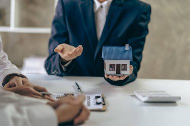 Emlakçılar, taksitle bir konut satın almanın faiz oranı anlaşmasının şartlarını tartışıyor. Müşterilerden kontrat imzalamalarını isteyin.