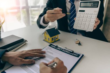 Emlakçılar, taksitle bir konut satın almanın faiz oranı anlaşmasının şartlarını tartışıyor. Müşterilerden kontrat imzalamalarını isteyin.