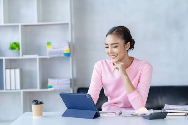 İnternette tabletle çalışan Asyalı kadın. Evden çalışan mutlu genç kadın.