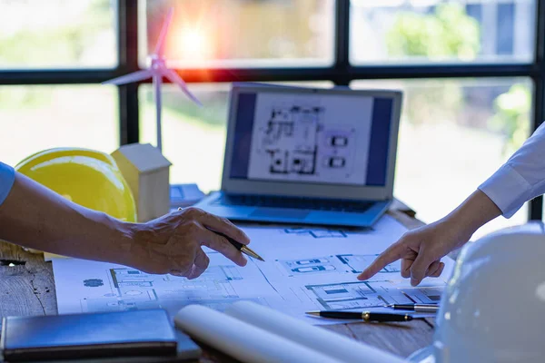 stock image Asian engineer Foreman or leader discussing home solar photovoltaic and wind turbine model in construction project and high voltage tower, renewable energy concept.