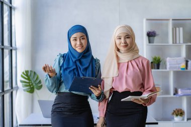 İki modern Müslüman kadın mali grafikler ve dizüstü bilgisayarla toplantı odasında iş görüşmeleri yapıyor ve tartışıyorlar.