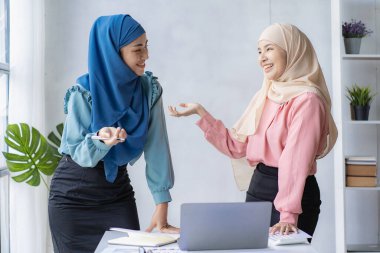 İki modern Müslüman kadın mali grafikler ve dizüstü bilgisayarla toplantı odasında iş görüşmeleri yapıyor ve tartışıyorlar.