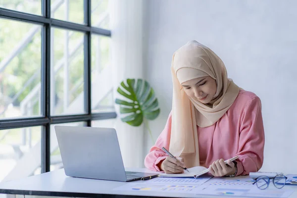stock image Management concept drives organizational growth of female leaders. Asian Muslim woman wearing hijab sits in the office of a start-up company. which is managed and run by young women