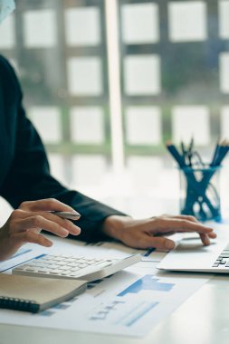 Dikey görünüm işadamı elinde bir kalem tutarak hesap makinesiyle çizelgelerle çalışır ve iş stratejilerini analiz eder. finansal istatistikler