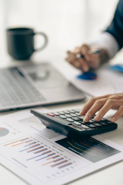 Dikey görünüm işadamı elinde bir kalem tutarak hesap makinesiyle çizelgelerle çalışır ve iş stratejilerini analiz eder. finansal istatistikler
